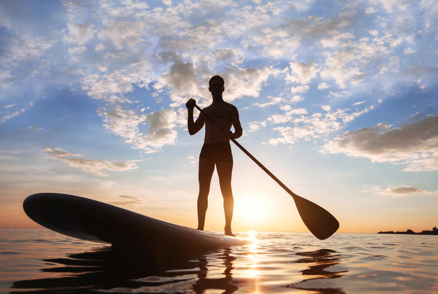 Stand Up Paddler paddelt in den Sonnenuntergang